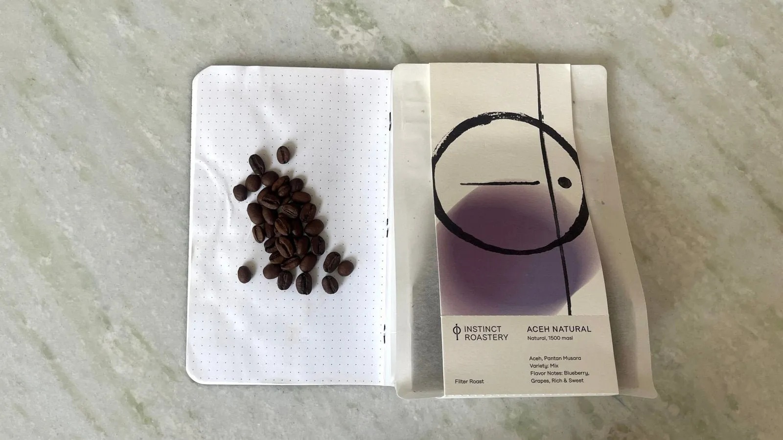 Rich coffee beans and a pour-over coffee dripper with a filter paper on a light marble surface, showcasing speciality coffee brewing from Barnaby Robson’s collection.