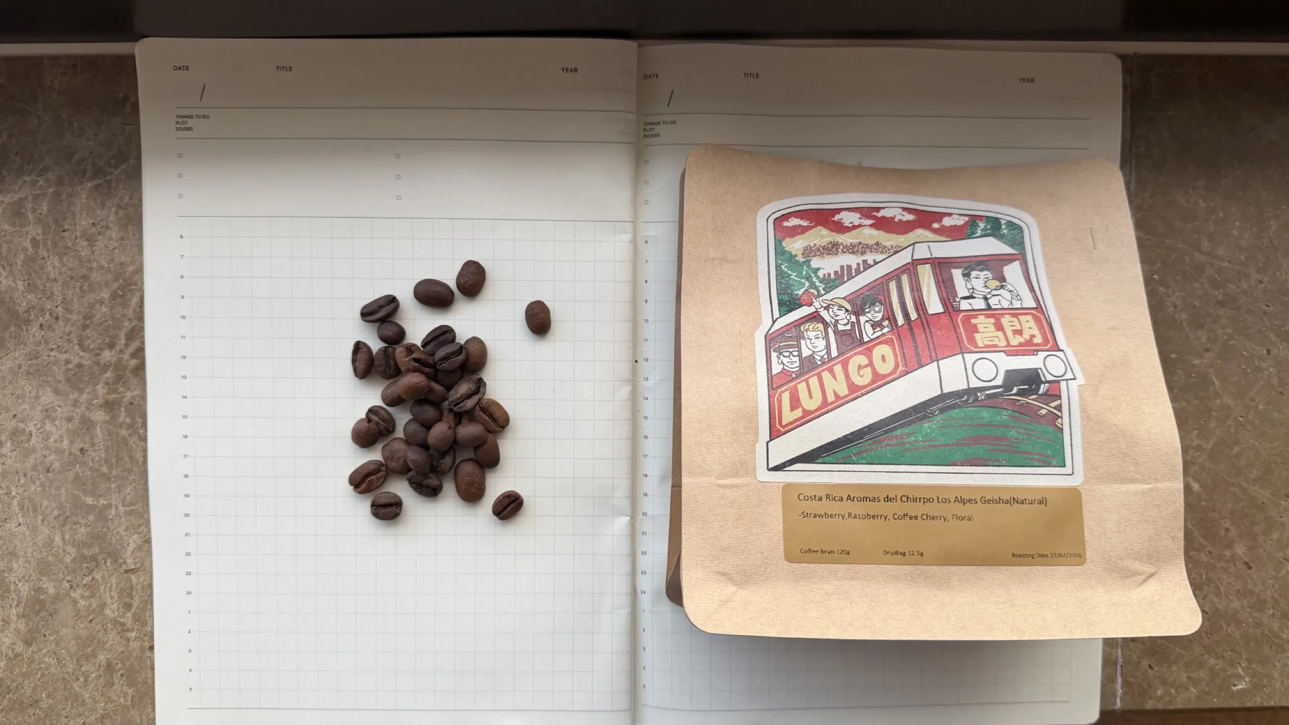 Lungo Los Alpes Geisha bag beside roasted beans on a grid notebook